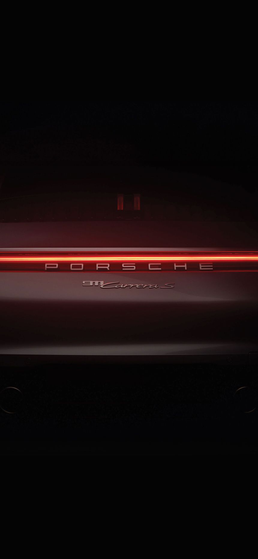 Rear view of a Porsche car in the dark with its illuminated red LED taillight strip.